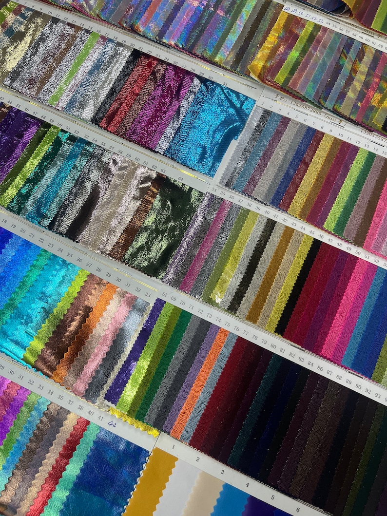 May include: A selection of fabric samples in diverse colours, such as silver, purple, teal, gold, and blue. Each swatch displays a unique shade and texture, organised in rows with numbered labels. The image includes text: 13626872885 (miss).