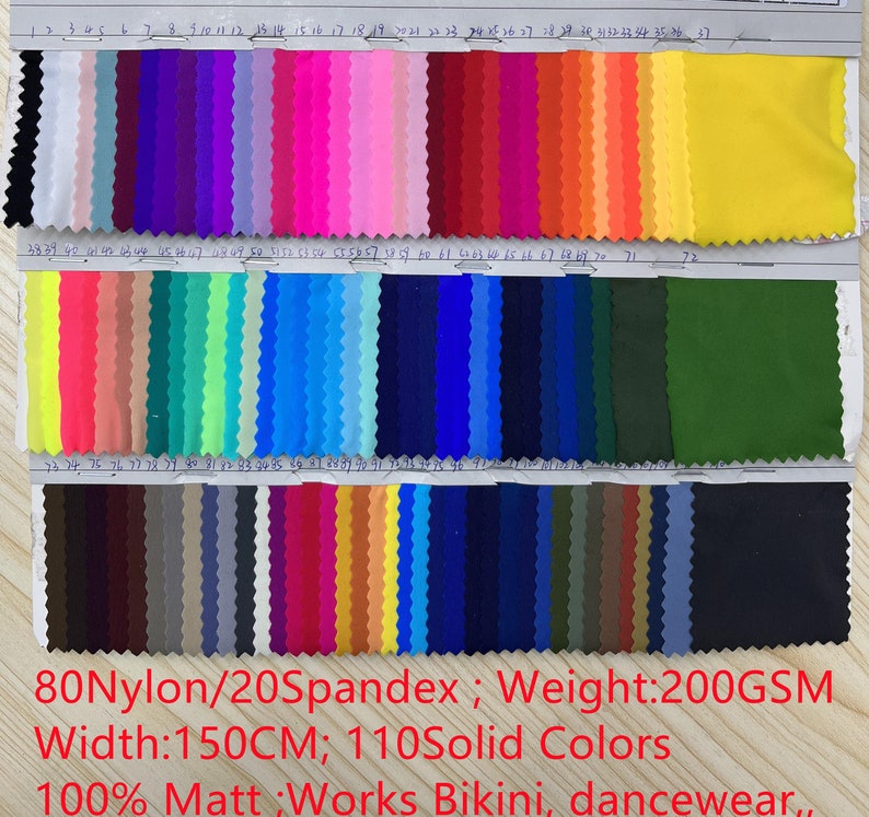 May include: A fabric swatch color chart featuring 110 solid colors with pinked edges, organized in three rows and numbered 1 through 110. Text states 80Nylon/20Spandex, 200GSM weight, 150CM width, and 100% Matt finish for bikini and dancewear.