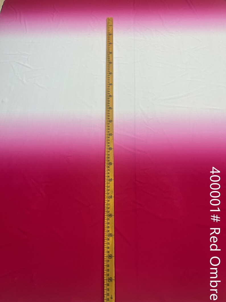 May include: A white and red ombre fabric with a wooden ruler measuring 96 inches. The fabric is smooth and has a slight sheen. The fabric is labeled "40001 # Red Ombre".