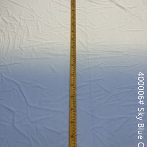 May include: A close-up of a light blue ombre fabric with a wooden ruler measuring 40 inches. The fabric is smooth and has a slight sheen. The ruler is marked in inches and has a metal tip.