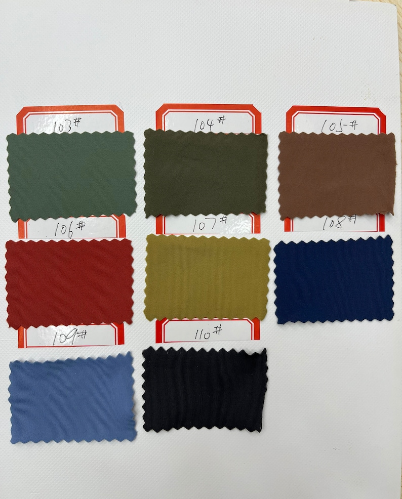 May include: A collection of eight rectangular fabric swatches with pinked edges, arranged in rows. Each swatch is labeled with a handwritten number from 103# to 110#. The colors include sage green, olive, brown, dark red, mustard, navy, blue, and black.