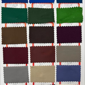 May include: A fabric swatch color chart featuring eighteen rectangular samples with pinked edges, arranged in a grid. Each swatch is labeled with a number from 67# to 84# in black ink, showcasing a diverse palette of blue, green, brown, purple, gray, and cream tones.