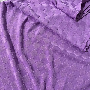Peut inclure: Tissu violet à motif à carreaux. Le tissu a une surface texturée légèrement en relief.