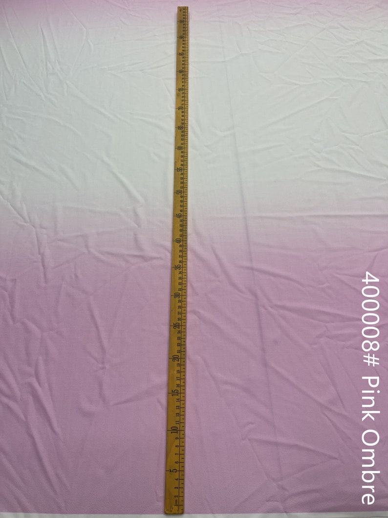 May include: A close-up of a light pink ombre fabric with a wooden ruler measuring 24 inches. The fabric is smooth and has a slight sheen. The text "400008# Pink Ombre" is visible in the bottom right corner of the image.