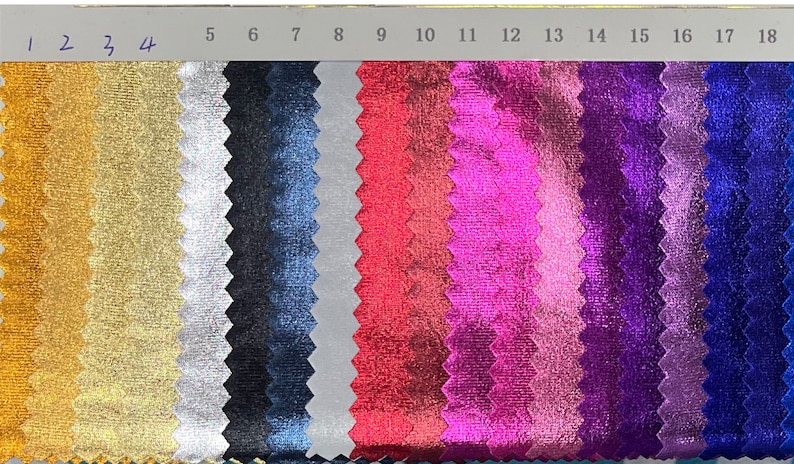 May include: A colour swatch displaying a range of metallic fabric samples. The samples vary in colour, from gold and silver to shades of blue, pink, and red. Numbers 1 to 18 are printed along the top of the swatch.