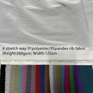 Könnte beinhalten: Ein weißer Rippenstoff-Swatch mit einer Farbmusterkarte mit 19 verschiedenen Farben. Der Stoff besteht aus 91 % Polyester und 9 % Elasthan. Der Stoff wiegt 260 Gramm pro Quadratmeter und ist 125 Zentimeter breit.