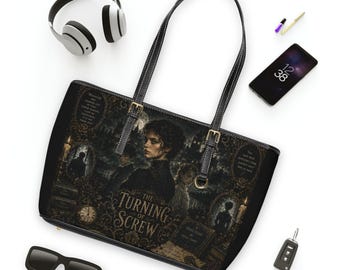 May include: A black tote bag featuring a gothic-style illustration with the text The Turning of Screw, a central figure, ornate frames, and candlelit scenes. The bag has two thin black shoulder straps with gold-toned buckles and metal hardware.