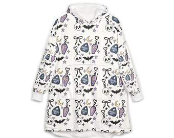 May include: A white oversized hooded sweatshirt featuring a repeating pattern of black skulls, bats, bows, yellow crescent moons, and purple coffin-shaped planchette charms with the text "ABSOLUTELY NOT" printed on them, complete with a front pocket.