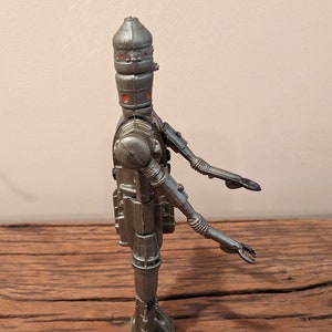 Peut inclure: Une figurine d'action Star Wars en argent d'un dro&iuml;de avec une t&ecirc;te en forme de d&ocirc;me et des bras et des jambes articul&eacute;s.