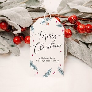 May include: White gift tag with a blue and green watercolor pine branch design. The tag says "Merry Christmas" in black script and "with love from the Reynolds Family" in black print.