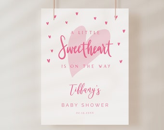May include: A pink heart with the text "A Little Sweetheart is on the way" and "Tiffany's Baby Shower 02.15.20XX" on a white background.