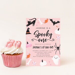 May include: Pink Halloween party invitation with black and white illustrations of a witch's hat, a black cat, a bat, a spider, a ghost, pumpkins, candy, and bones. The text reads "Jasmine is a Spooky one" and "Jasmine's 1st Boo-Day".