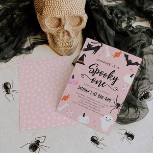 May include: A pink and black Halloween party invitation with a skull, bats, candy, and a ghost. The invitation reads "Jasmine is a Spooky One" and "Jasmine's 1st Boo-Day".