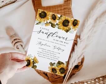 May include: A white baby shower invitation featuring a sunflower design. The text reads "A Little Sunflower Is On The Way" and includes the name "Angelina Godfrey".
