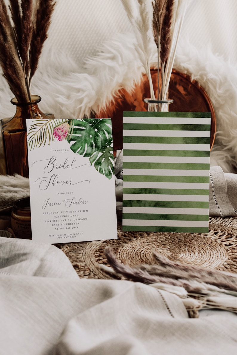 Puede incluir: Una invitaci&oacute;n a un baby shower de tem&aacute;tica tropical con una tarjeta RSVP a rayas verdes y blancas. La invitaci&oacute;n presenta una ilustraci&oacute;n de acuarela de hojas tropicales y una flor rosa. El texto dice "&Uacute;nete a nosotros para un Baby Shower en honor a Jessica Sanders S&aacute;bado, 25 de julio a las 3:00 PM Flamingo Cafe 7344 98th Ave SE, Chicago RSVP a Chelsea al 763.446.2944 Jessica est&aacute; registrada en Pottery Barn"