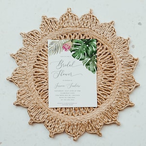 Puede incluir: Una invitaci&oacute;n de ducha nupcial blanca con hojas tropicales y una flor rosa. El texto dice "Join us for a Bridal Shower in honor of Jessica Trailers, S&aacute;bado, 25 de julio a las 3:00 p. m., Flamingo Cafe, 7344 58th Ave SE, Chicago, RSVP a Chelsea al 763.446.2944, Jessica est&aacute; registrada en Pottery Barn."