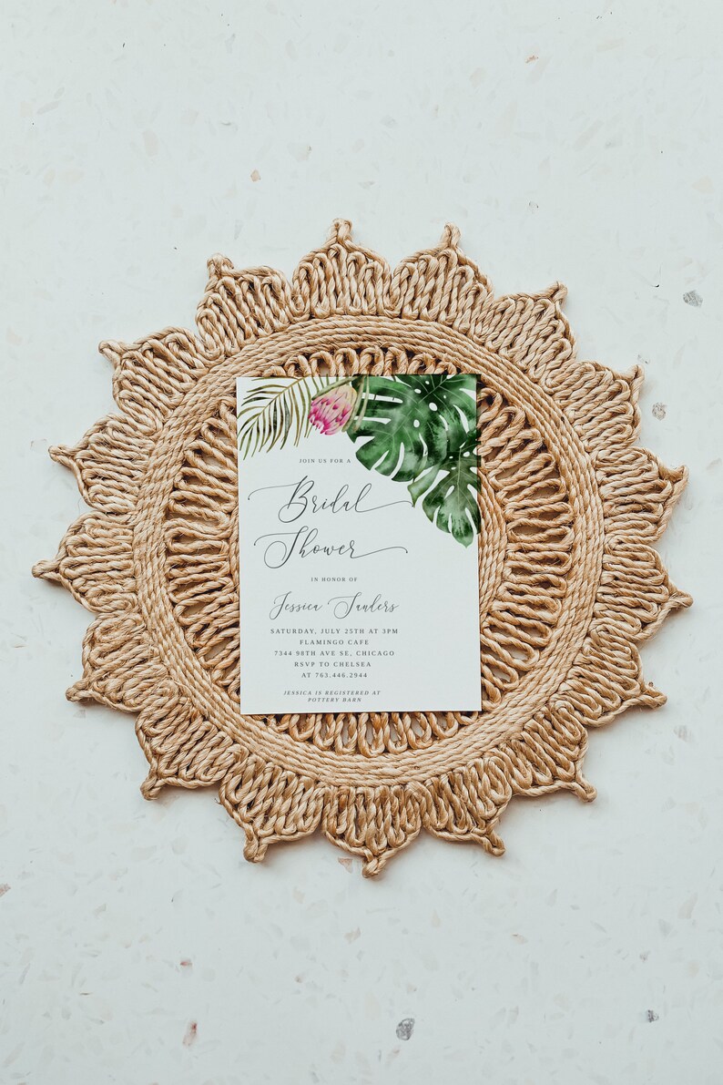 Puede incluir: Una invitaci&oacute;n de ducha nupcial blanca con hojas tropicales y una flor rosa. El texto dice "Join us for a Bridal Shower in honor of Jessica Trailers, S&aacute;bado, 25 de julio a las 3:00 p. m., Flamingo Cafe, 7344 58th Ave SE, Chicago, RSVP a Chelsea al 763.446.2944, Jessica est&aacute; registrada en Pottery Barn."