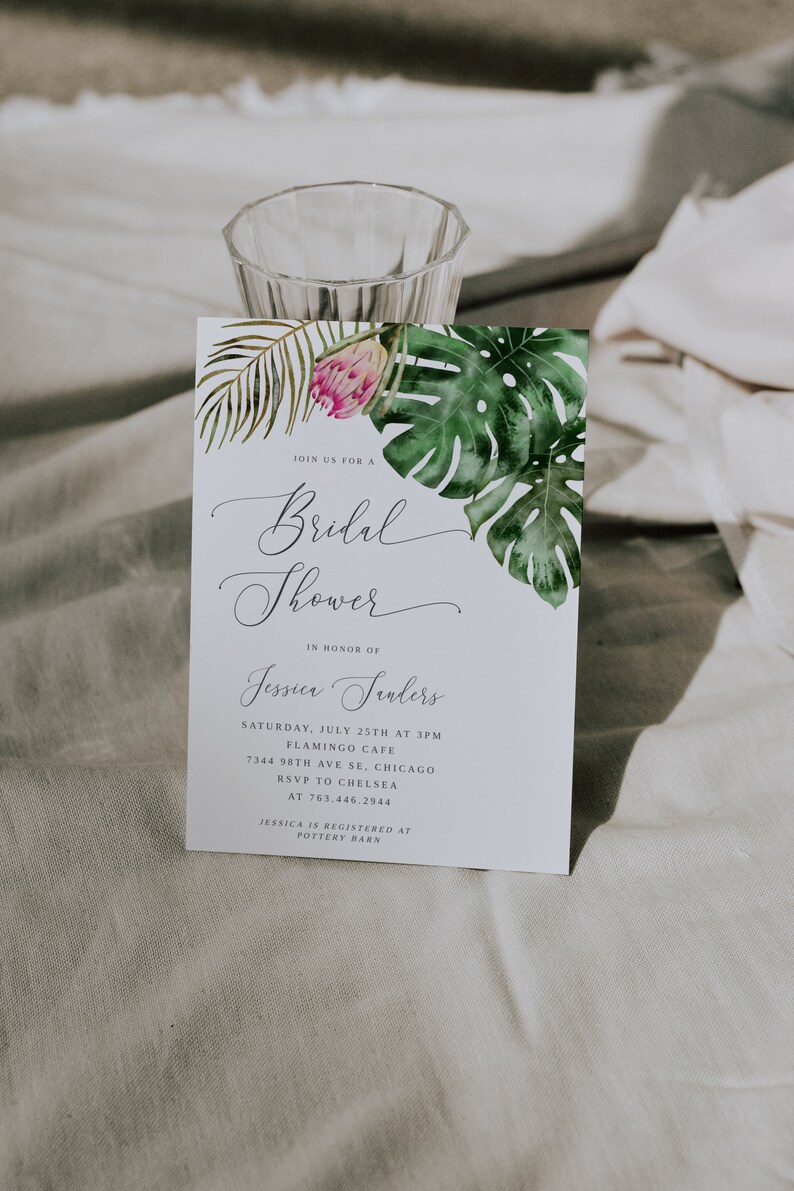 Puede incluir: Una invitaci&oacute;n de despedida de soltera blanca con un tema tropical. La invitaci&oacute;n presenta una ilustraci&oacute;n de acuarela de hojas de palma verdes y una flor rosa. El texto de la invitaci&oacute;n dice: "&Uacute;nete a nosotros para una despedida de soltera en honor a Jessica Sanders. S&aacute;bado, 25 de julio a las 3:00 p. m. Flamingo Cafe 7344 98th Ave SE, Chicago RSVP a Chelsea al 763.446.2944 Jessica est&aacute; registrada en Pottery Barn."