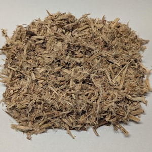 May include: A close-up of a pile of light brown, shredded plant material. The texture is fibrous and slightly coarse, with visible pieces of wood and plant fibres. The material is likely used for crafting, gardening, or as a natural product.
