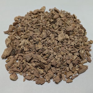 May include: A pile of dried, brown and reddish-brown bark chips. The bark is broken into small, irregular pieces.