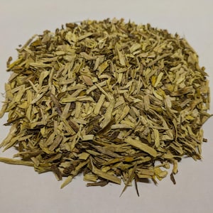 May include: A pile of dried, light brown and yellow herbal tea leaves.