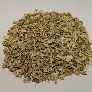 May include: A close-up of a pile of dried, light brown and green herbs. The herbs are broken into small pieces and have a rough texture.