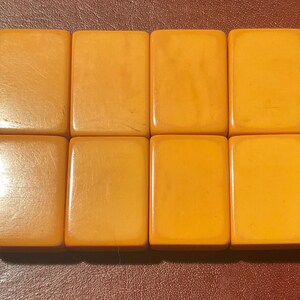 Puede incluir: Ocho baldosas rectangulares de color &aacute;mbar dispuestas en dos filas. Las baldosas tienen una superficie lisa y brillante con sutiles variaciones de tono. Las baldosas son probablemente componentes de un juego.