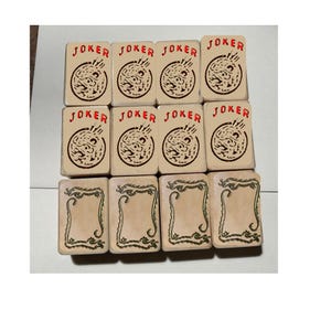 May include: A collection of twelve rectangular tiles arranged in three rows. The top two rows feature eight tiles with the word JOKER in red text above a circular graphic. The bottom row contains four tiles with a green dragon border design.