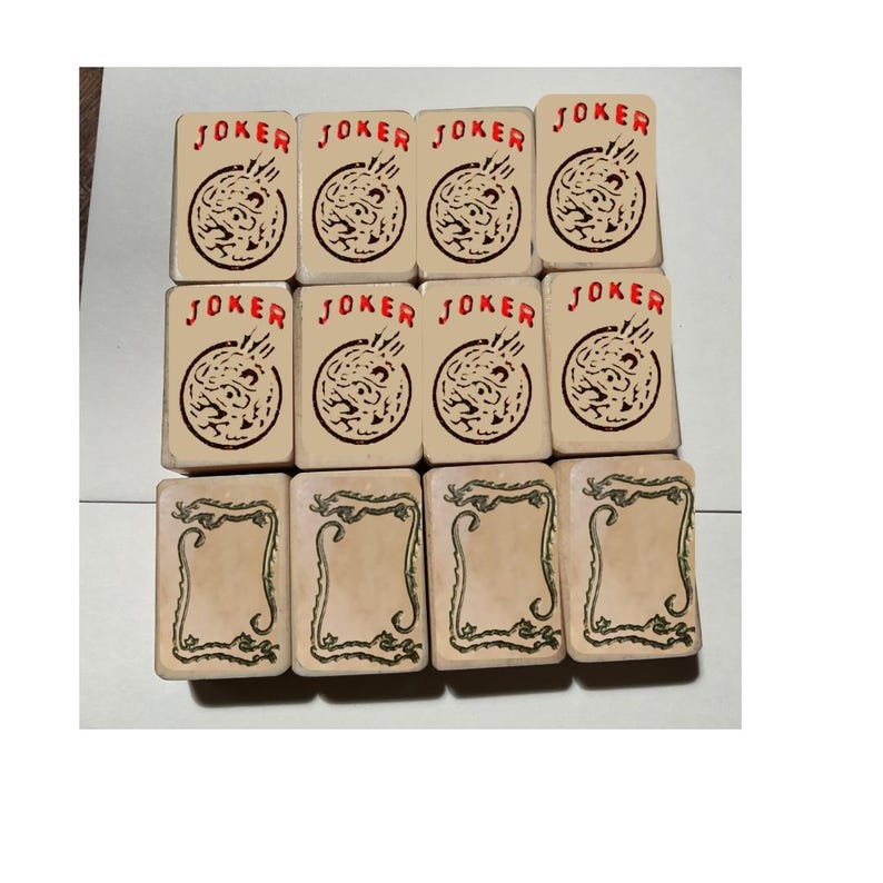May include: A collection of twelve rectangular tiles arranged in three rows. The top two rows feature eight tiles with the word JOKER in red text above a circular graphic. The bottom row contains four tiles with a green dragon border design.