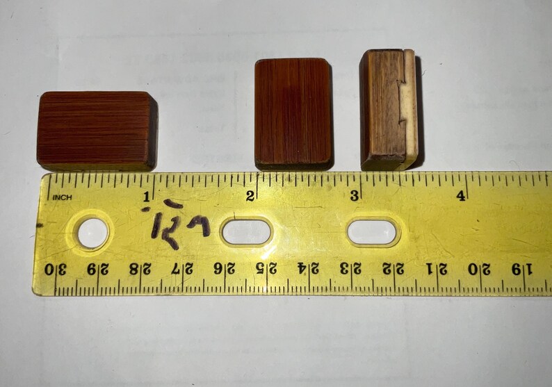 以下が含まれることがあります： さまざまなサイズと色の3つの小さな長方形の木製ボックスが、黄色の定規の隣に表示されています。ボックスは赤茶色の木材でできています。定規はセンチメートル単位の測定値を表示します。