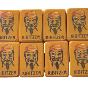 May include: Eight rectangular game tiles with a yellow background. Each tile features a black and white illustration of a man with a long beard and a hat. The word "KIBITZER" is printed in black at the bottom of each tile.