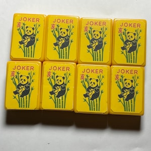 May include: Eight yellow Mahjong tiles with the word "JOKER" and a panda bear illustration. The panda is black and white, sitting in front of green bamboo stalks. The tiles are rectangular and have rounded corners.