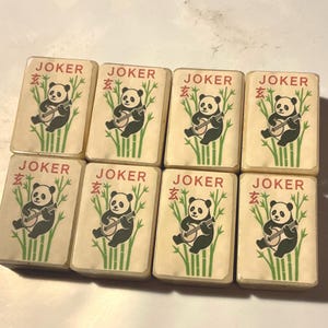 May include: Eight vintage Mahjong joker tiles. Each tile features a panda playing a stringed instrument, with bamboo stalks in the background. The word "JOKER" is printed at the top, with a Chinese character above the panda.