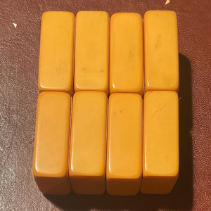 Puede incluir: Ocho fichas de juego rectangulares de color &aacute;mbar dispuestas en dos filas de cuatro. Las fichas tienen bordes redondeados y un acabado liso y brillante. Las fichas son probablemente para un juego de mesa.