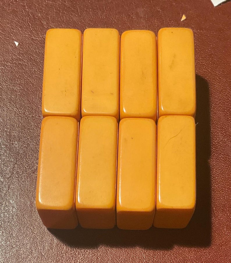 Puede incluir: Ocho fichas de juego rectangulares de color &aacute;mbar dispuestas en dos filas de cuatro. Las fichas tienen bordes redondeados y un acabado liso y brillante. Las fichas son probablemente para un juego de mesa.