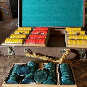 Pu&ograve; includere: Set di fiches da poker vintage con custodia in legno marrone. La custodia aperta rivela pile di fiches gialle, rosse e verdi. L'interno &egrave; in feltro verde. Una scatola di legno separata contiene pi&ugrave; fiches verdi.
