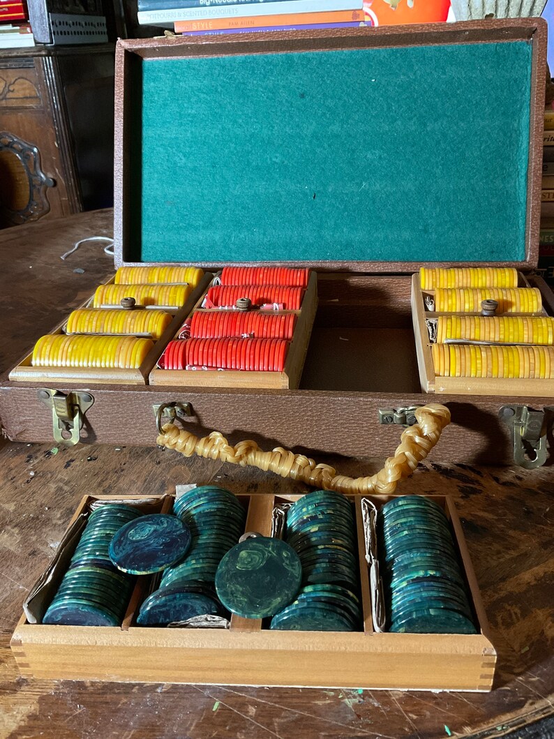 Pu&ograve; includere: Set di fiches da poker vintage con custodia in legno marrone. La custodia aperta rivela pile di fiches gialle, rosse e verdi. L'interno &egrave; in feltro verde. Una scatola di legno separata contiene pi&ugrave; fiches verdi.