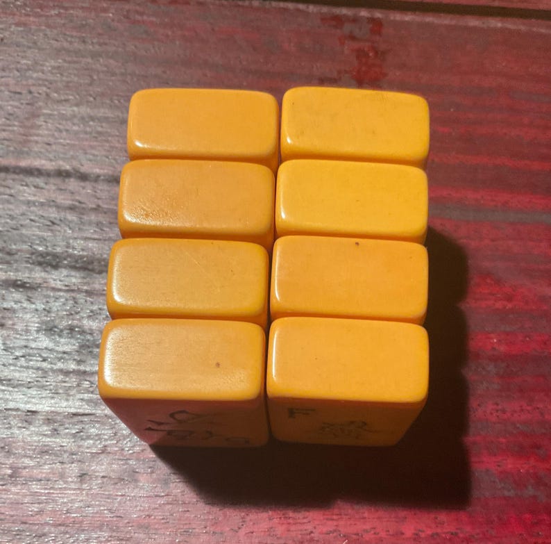 May include: Eight rectangular, amber-colored tiles are arranged in two columns. The tiles have rounded edges and a glossy finish. Some tiles have faint markings on their sides. The tiles appear to be made of a solid, uniform material.