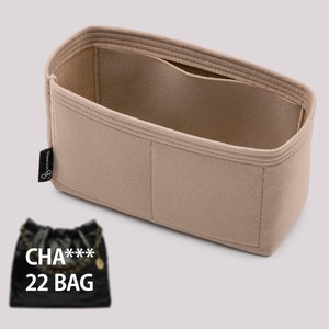 Puede incluir: Organizador de bolso de fieltro beige con múltiples compartimentos. El organizador está diseñado para caber dentro de un bolso de mano. El texto "CHA*** 22 BAG" es visible en una bolsa negra en primer plano.