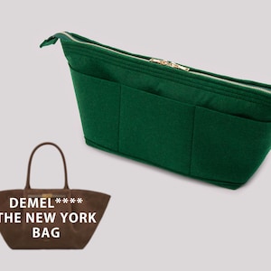 Puede incluir: Una bolsa de fieltro verde con varios bolsillos y una cremallera dorada. La bolsa está diseñada para caber dentro de una bolsa de mano más grande. El texto "DEMEL **** THE NEW YORK BAG" está impreso en una bolsa de mano de cuero marrón.