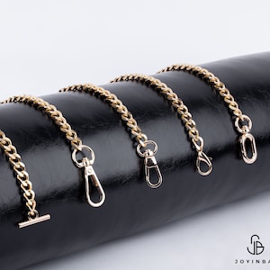 May include: Five gold chain straps with different lengths and clasps. The chains are displayed on a black leather surface.