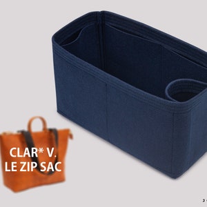 May include: A dark blue felt bag organizer with multiple compartments and a handle. The organizer is designed to fit inside a larger bag, helping to keep it organized.