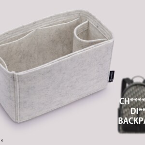 Op de afbeelding: Een witte vilt tas organizer met meerdere compartimenten. De organizer is ontworpen om in een luxe handtas te passen. De afbeelding toont ook een zwart-wit gepatroneerde rugzak met de tekst "CH****** DI** BACKPACK".