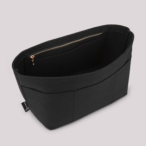 May include: Black felt bag organizer with multiple compartments and a zippered top closure. The interior features pockets for organization. The bag has a gold-colored zipper and a small label on the side.