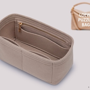 Peut inclure: Organiseur de sac en feutre beige avec plusieurs compartiments et une poche zippée. L'organisateur est conçu pour s'adapter à un sac Loewe Puzzle.