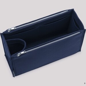 May include: A navy blue felt bag organiser with multiple compartments and zipper closures. The organiser is designed to fit inside a larger bag, helping to keep items organised.