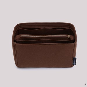 K&ouml;nnte beinhalten: Ein brauner Filz-Taschenorganizer mit mehreren F&auml;chern und einer Rei&szlig;verschlusstasche. Der Organizer hat ein kleines schwarzes Etikett mit dem Text "Joyinbag" darauf.