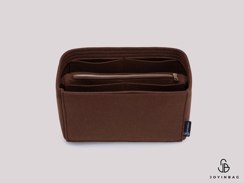 K&ouml;nnte beinhalten: Ein brauner Filz-Taschenorganizer mit mehreren F&auml;chern und einer Rei&szlig;verschlusstasche. Der Organizer hat ein kleines schwarzes Etikett mit dem Text "Joyinbag" darauf.