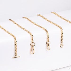 May include: Five gold chain straps with different lengths and clasps. The chains are on a white background.