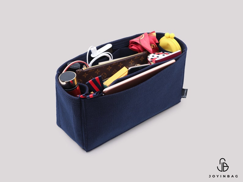 May include: A navy blue felt bag organizer with multiple compartments and pockets. The organizer is filled with various items, including a phone, wallet, and makeup.